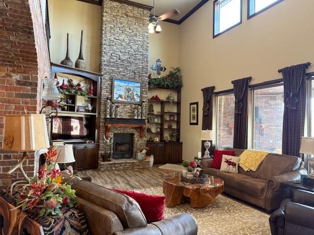 living room featuring crown molding, a fireplace, wood-type flooring, and a towering ceiling