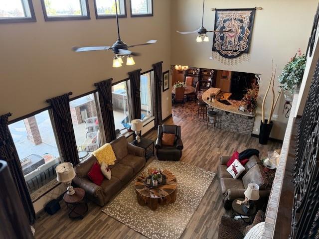 living room featuring wood-type flooring, ceiling fan, and a high ceiling