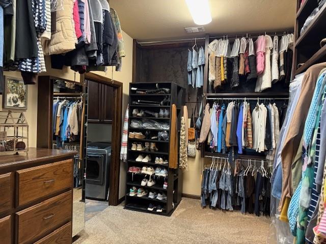 spacious closet featuring washer / dryer and light colored carpet