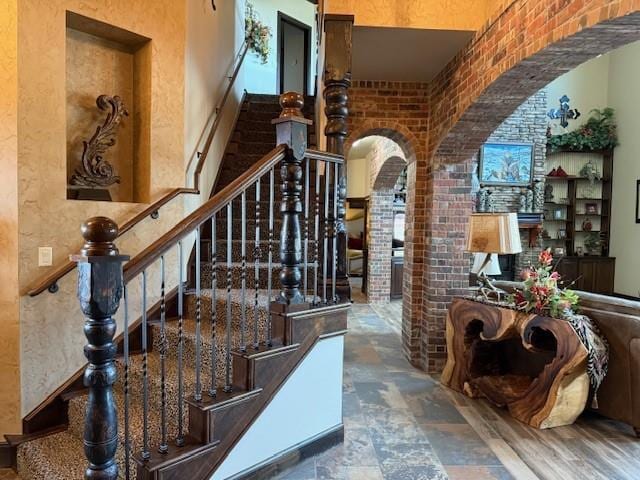 staircase with a high ceiling and brick wall