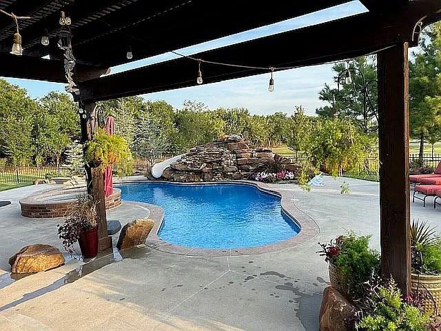 view of pool featuring a water slide, a jacuzzi, and a patio area