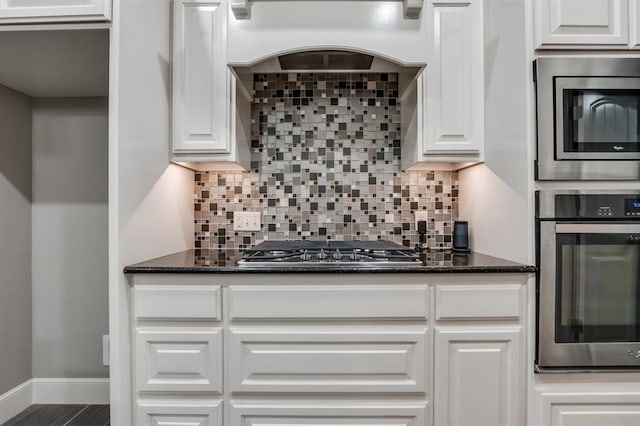 kitchen with white cabinetry, appliances with stainless steel finishes, decorative backsplash, and premium range hood