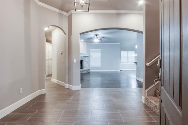 foyer entrance featuring a ceiling fan, arched walkways, crown molding, and stairway