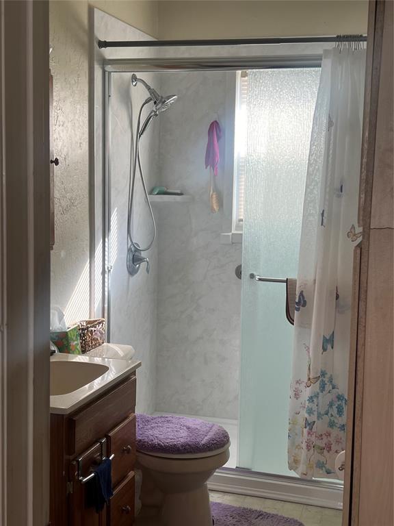 506 N Broadway St, Marlow, OK 73055 - bathroom featuring walk in shower, vanity, and toilet