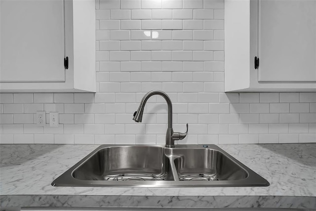 details with light stone countertops, sink, and white cabinets