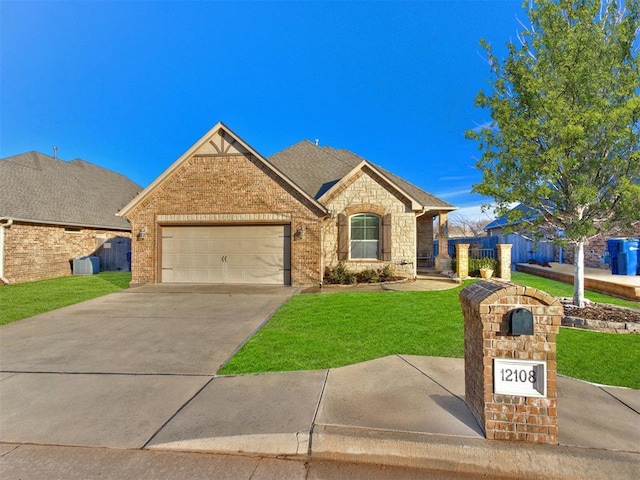 view of front of house with stone siding, driveway, a front yard, a garage, and a shingled roof