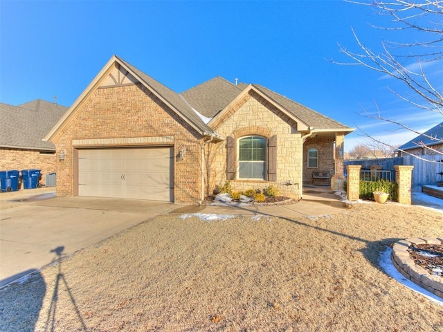 view of front of property with fence, an attached garage, brick siding, roof with shingles, and driveway