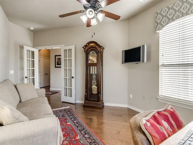 living area with baseboards, wood finished floors, french doors, and a ceiling fan