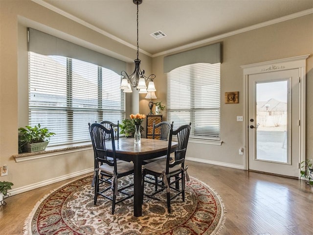 dining area featuring ornamental molding, visible vents, a notable chandelier, and plenty of natural light