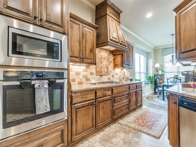 kitchen with light stone counters, tasteful backsplash, appliances with stainless steel finishes, custom range hood, and ornamental molding
