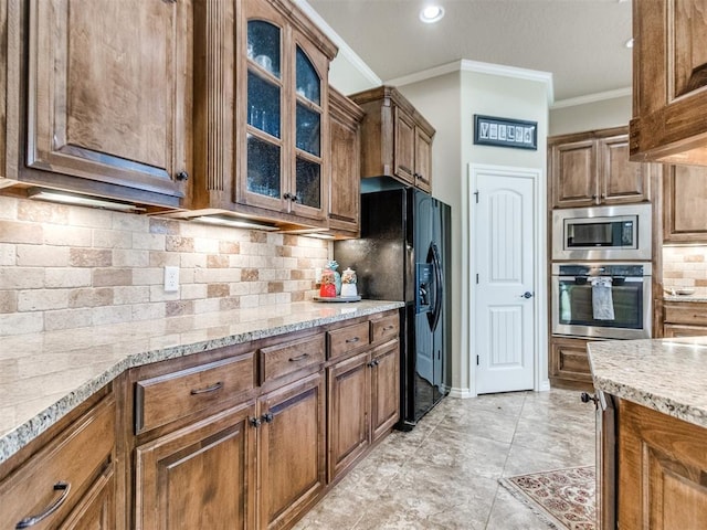 kitchen featuring brown cabinetry, ornamental molding, stainless steel appliances, light stone counters, and backsplash