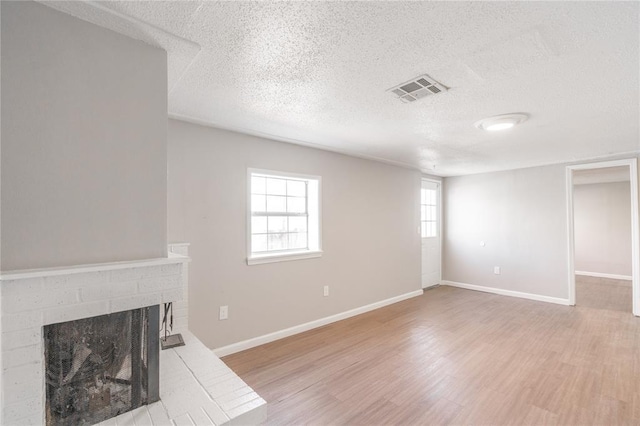 living room with a fireplace, light hardwood / wood-style flooring, and a textured ceiling