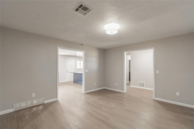 spare room with a textured ceiling and light hardwood / wood-style floors