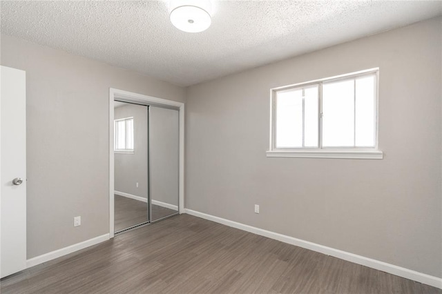 unfurnished bedroom with dark hardwood / wood-style flooring, a closet, and a textured ceiling