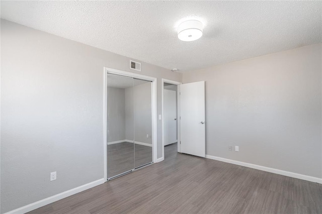 unfurnished bedroom featuring dark hardwood / wood-style floors, a closet, and a textured ceiling