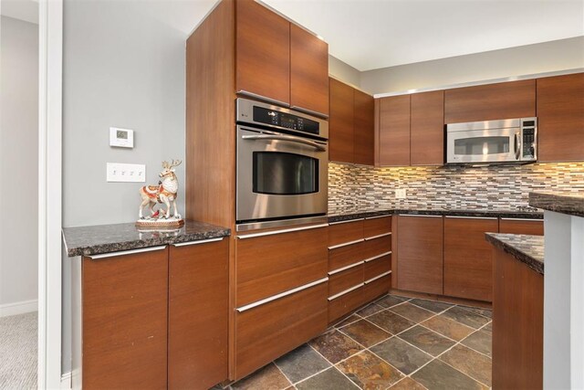 5900 Mosteller Dr Unit St32, Oklahoma City, OK 73112 - kitchen featuring stainless steel appliances, decorative backsplash, brown cabinetry, dark stone countertops, and modern cabinets