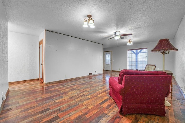 living room with dark wood-type flooring, ceiling fan, and a textured ceiling