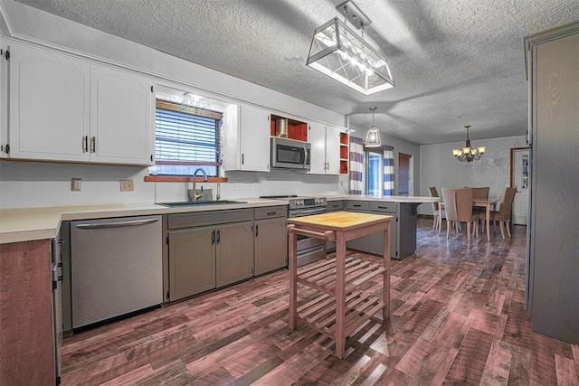 kitchen with sink, decorative light fixtures, appliances with stainless steel finishes, dark hardwood / wood-style flooring, and white cabinets