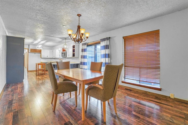 dining space featuring dark wood-type flooring, a chandelier, and a textured ceiling