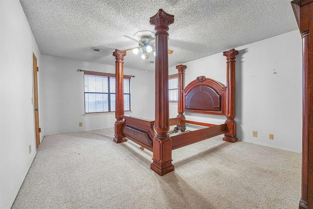 carpeted bedroom featuring ceiling fan, a textured ceiling, and ornate columns