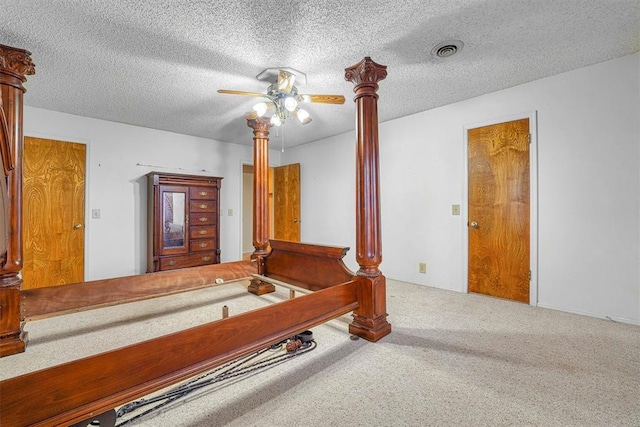 carpeted bedroom featuring decorative columns, a textured ceiling, and ceiling fan