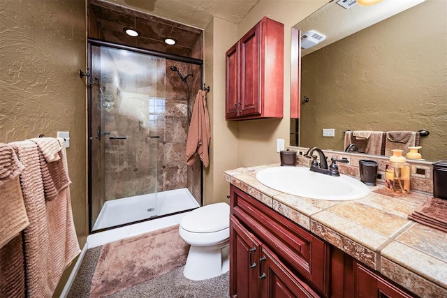 bathroom featuring vanity, toilet, and a shower with shower door