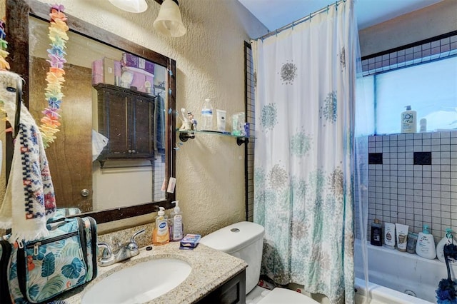 bathroom with a textured wall, shower / bath combo with shower curtain, vanity, and toilet