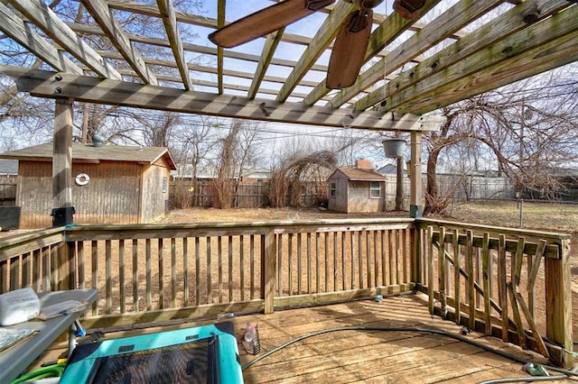 wooden deck featuring an outbuilding, a storage unit, a fenced backyard, and a pergola