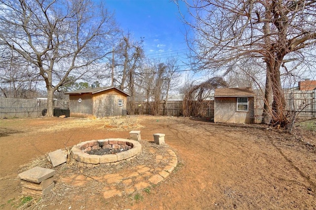 view of yard with a fire pit, a storage shed, an outdoor structure, and a fenced backyard