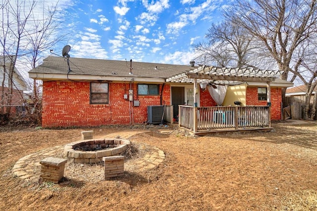 rear view of house featuring a wooden deck, a fire pit, central AC, and brick siding