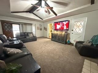 living area with lofted ceiling with beams, carpet flooring, a fireplace, and ceiling fan