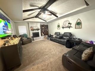 carpeted cinema room featuring vaulted ceiling with beams, a fireplace, and a ceiling fan
