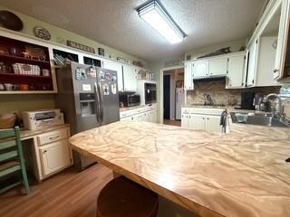 kitchen featuring a peninsula, stainless steel fridge with ice dispenser, light countertops, and a sink