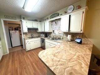 kitchen featuring white cabinetry, a textured ceiling, refrigerator, and light countertops