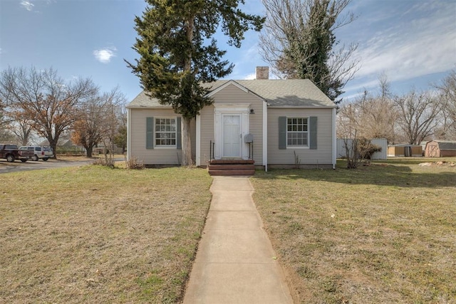 bungalow-style home with entry steps, a chimney, and a front lawn