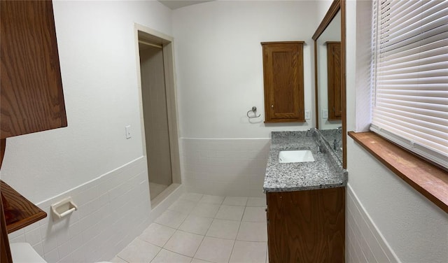 bathroom featuring tile patterned floors, vanity, tile walls, and a shower