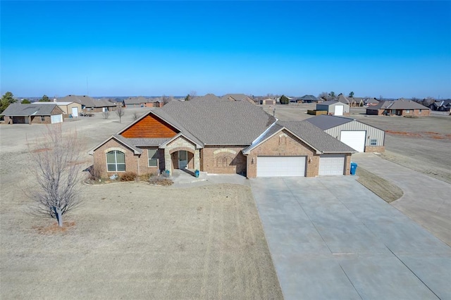 view of front facade with driveway, a shingled roof, a residential view, an attached garage, and brick siding