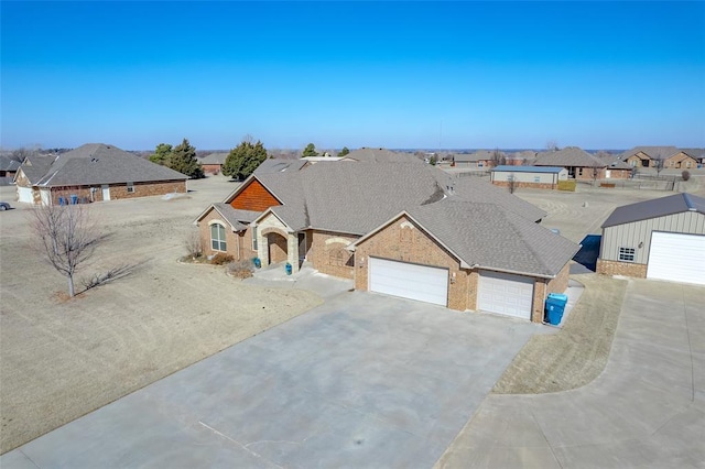 view of front of property featuring a garage, driveway, a shingled roof, a residential view, and brick siding