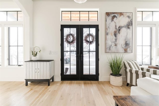 foyer entrance featuring french doors, baseboards, and light wood finished floors