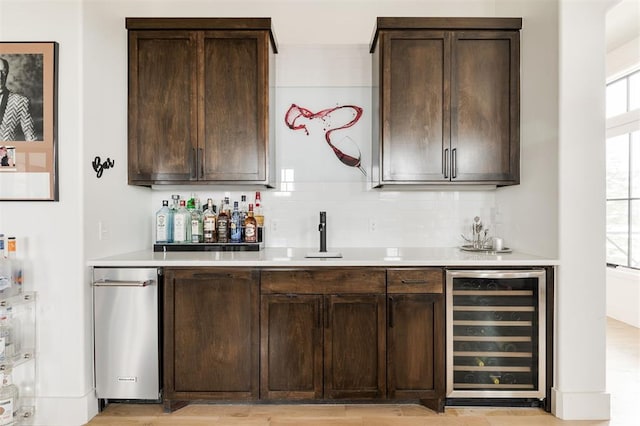 bar featuring a sink, beverage cooler, decorative backsplash, and indoor wet bar