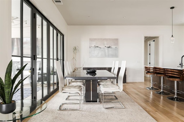 dining space with light wood-style flooring, visible vents, and baseboards