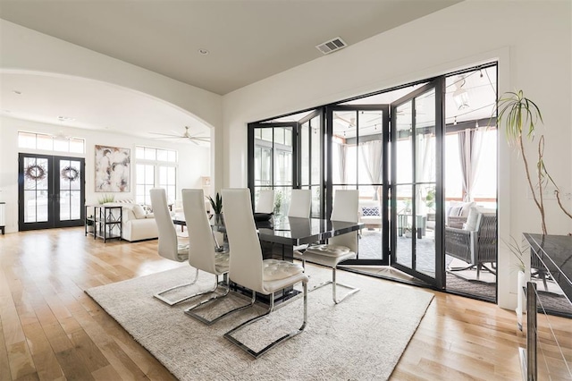 living room featuring arched walkways, french doors, wood finished floors, and visible vents