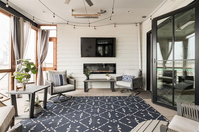 sunroom featuring a glass covered fireplace and ceiling fan