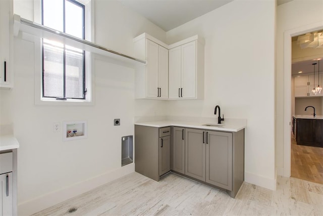 washroom with cabinet space, baseboards, a sink, washer hookup, and electric dryer hookup