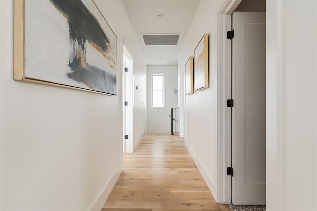 corridor with light wood-type flooring, visible vents, and baseboards