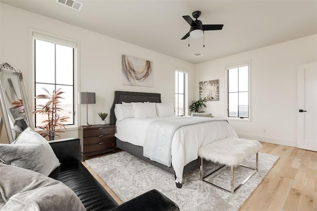 bedroom featuring light wood finished floors, baseboards, visible vents, and ceiling fan