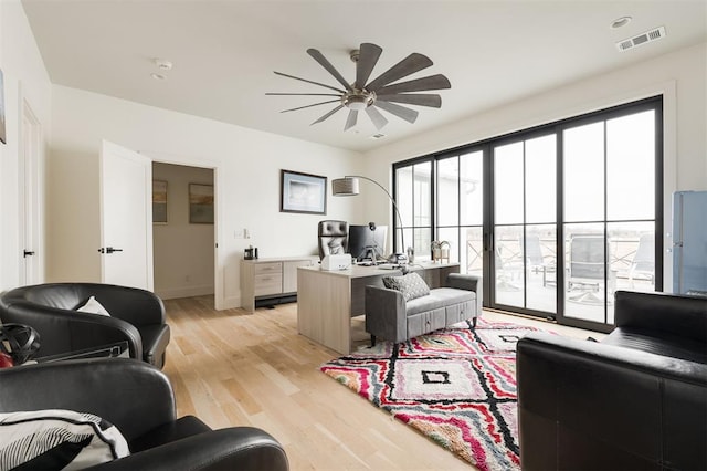 living room featuring light wood-style floors, visible vents, ceiling fan, and baseboards