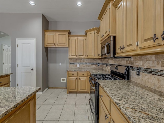 kitchen featuring light stone counters, appliances with stainless steel finishes, light brown cabinetry, and light tile patterned flooring