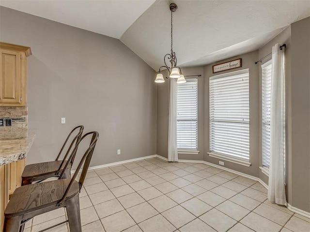 tiled dining area featuring lofted ceiling and a chandelier