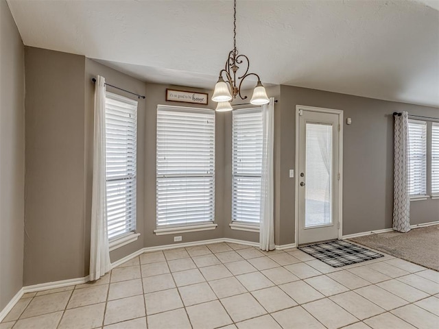 unfurnished dining area featuring light tile patterned floors and an inviting chandelier